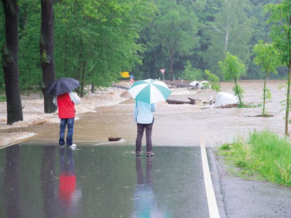 2 Passanten stehen auf der überfluteten Straße bei Regen und Hochwasser